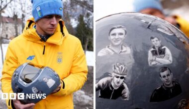 Ukraine's skeleton racer Vladyslav Heraskevych holds his helmet, which depicts victims of his country's war with Russia,
