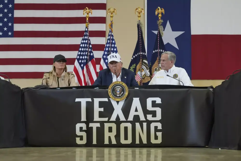 President Donald Trump speaks as first lady Melania Trump, left, and Texas Gov. Greg Abbott listen during a roundtable discussion with first responders and local officials in Kerrville, Texas earlier this month after the floods. 
