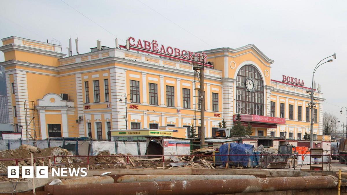 A yellow and white building with red lettering in Russian stands above construction works.