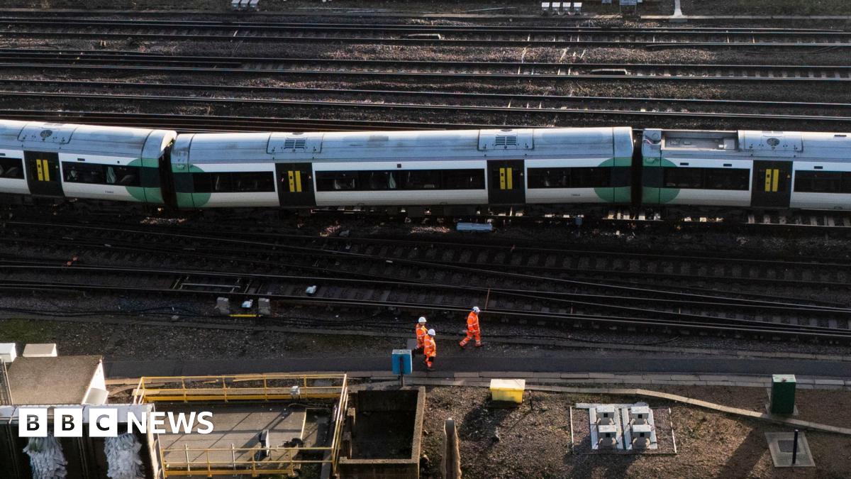 An aerial image showing a train that has come off the tracks and some engineers nearby wearing orange high-viz clothing