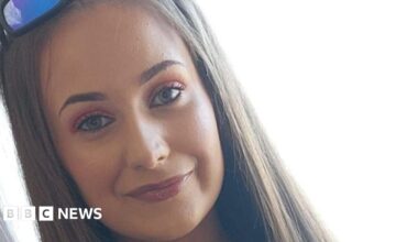 Chloe smiling at the camera. She has long straight light brown hair. She is wearing sunglasses on top of her head.