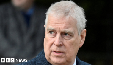 A head and shoulders image of a man with grey hair and brown eyes looking off to his right. He is wearing a blue herringbone jacket