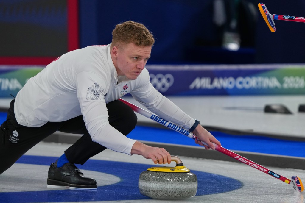 Bobby Lammie of Great Britain releases a curling stone while holding a broom during a curling match.