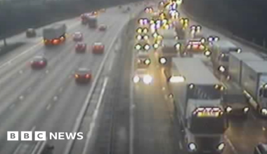 Travel builds up on the M6 with cars and lorries, with their lights on, come to a halt in the dark with traffic flowing on the other carriageway