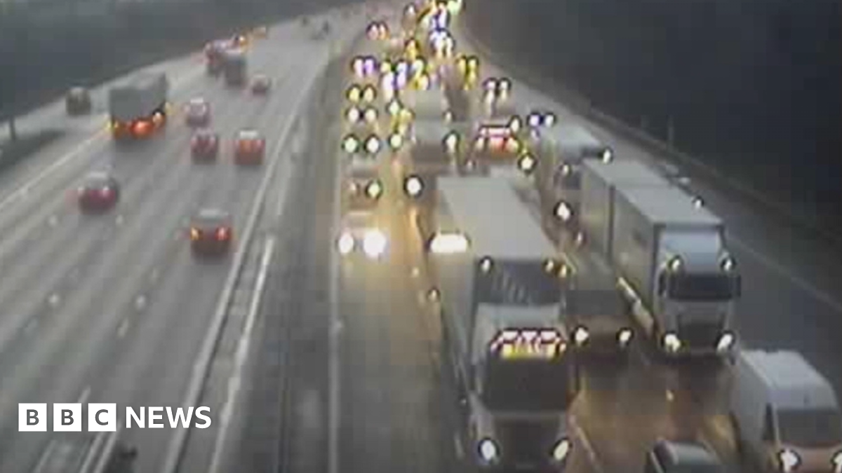 Travel builds up on the M6 with cars and lorries, with their lights on, come to a halt in the dark with traffic flowing on the other carriageway