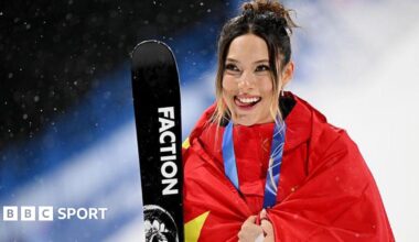 Eileen Gu with her silver medal around her neck, wrapped in a Chinese flag