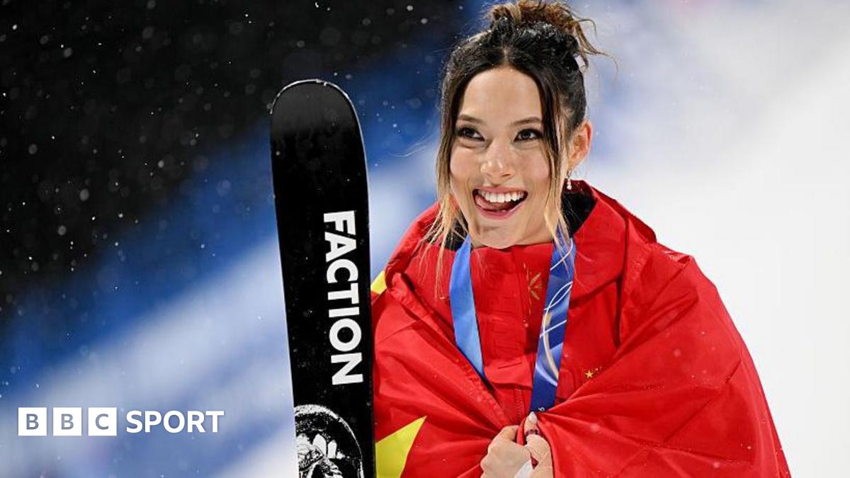 Eileen Gu with her silver medal around her neck, wrapped in a Chinese flag