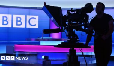 A person walks with an umbrella outside BBC Broadcasting House in London in November 2025
