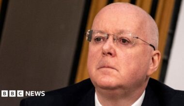 Peter Murrell, who is bald with glasses, in a close-up shot. He is wearing a dark suit, white shirt.