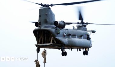 Members of the British military hang on ropes from a helicopter during a training exercise at Otterburn Training Area