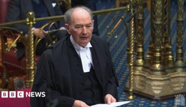 Lord Forsyth dressed in a black cloak and white shirt. He is holding a piece of paper as he addresses the House of Lords.