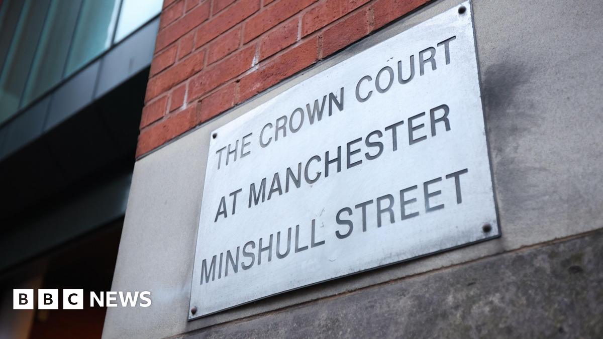 A metal sign botled to a concrete wall engraved with the words .The Crown Court at Manchester Minshull Street'.