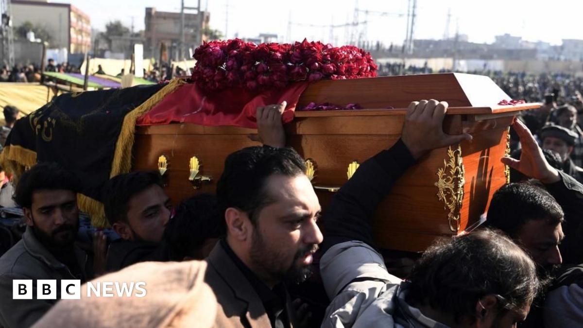 Several men carry a coffin through a huge crowd
