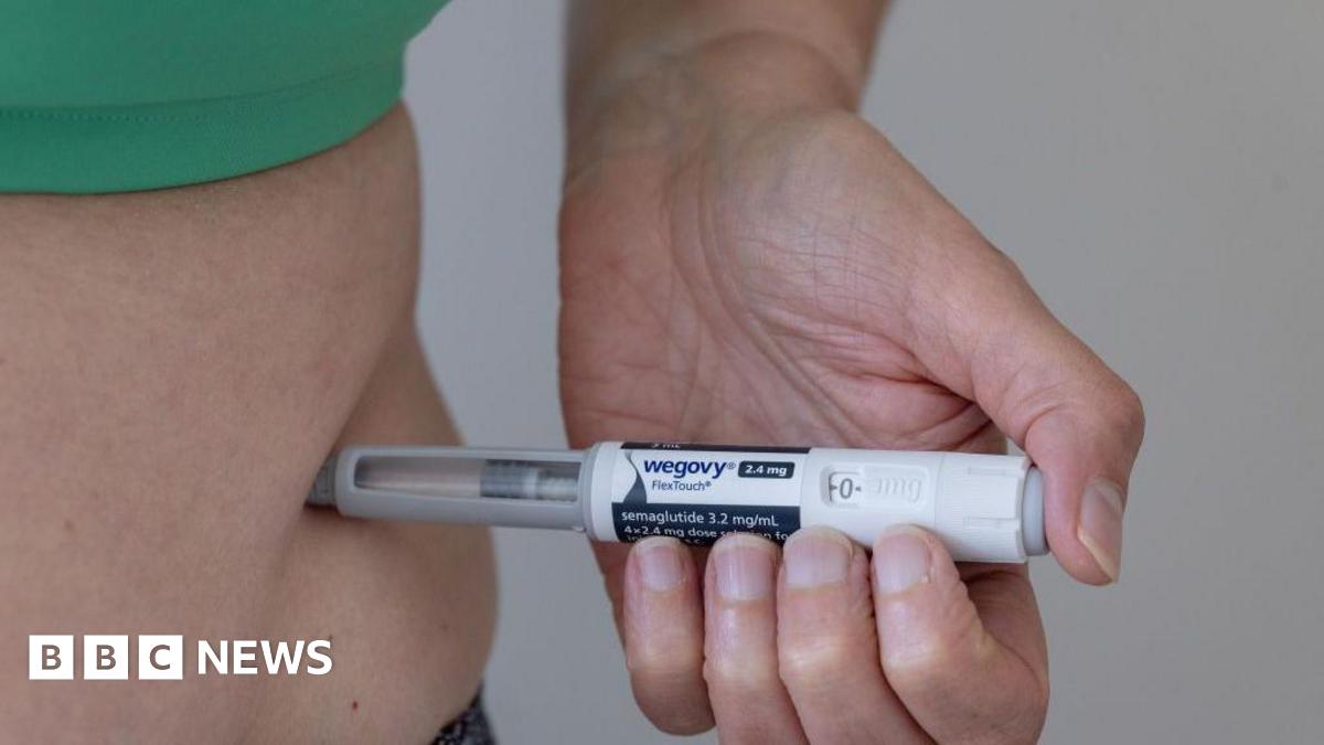 A person wearing a green top injects Wegovy into their stomach.