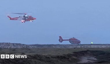 Two helicopters around a coastline