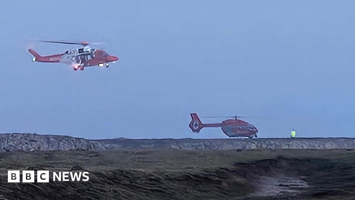 Two helicopters around a coastline