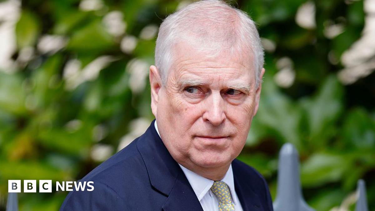 Andrew Mountbatten-Windsor wearing a navy suit, white shirt and yellow printed tie