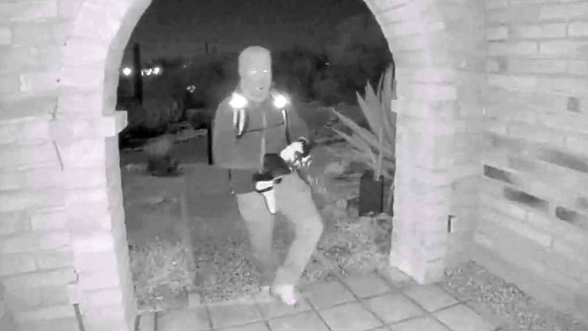 A view from a doorbell camera showing an armed individual outside the residence of Nancy Guthrie in Tucson, Arizona
