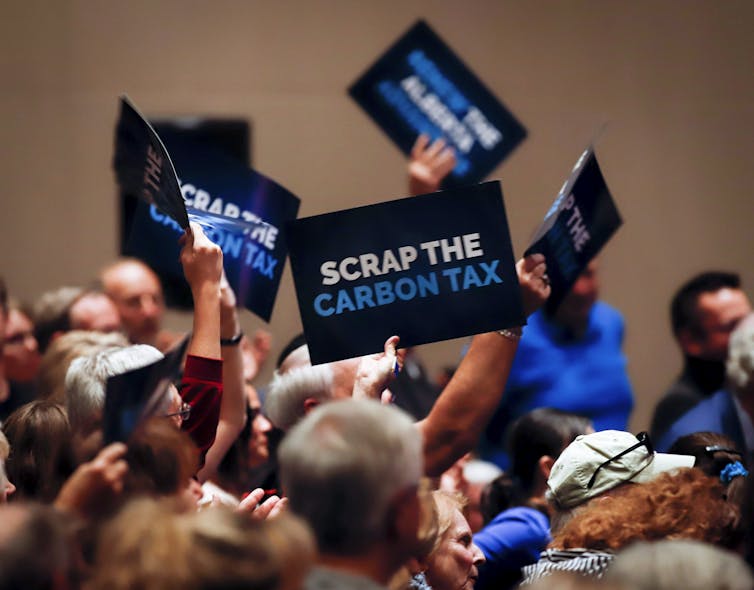 People wave signs reading Axe the Carbon Tax.