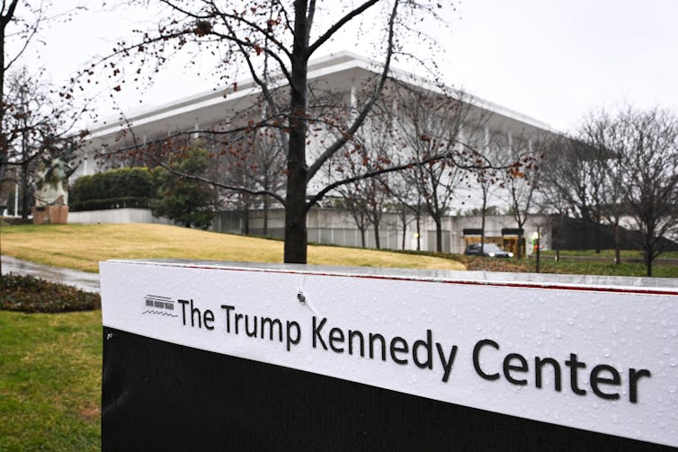 A view of the Kennedy Center, with a sign saying 'The Trump Kennedy Center' in the foreground.