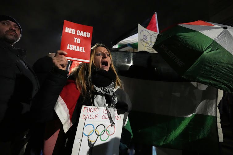 Protesters hold Palestinian flags and signs that say 'red card to Israel'