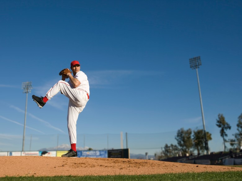A baseball pitcher on the mound, in the middle of his delivery, and ready to throw the ball.