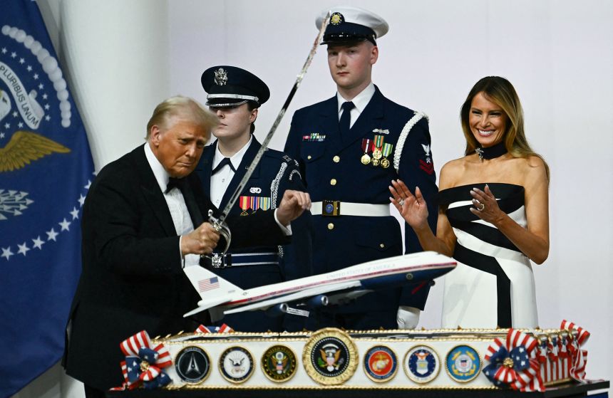 Donald Trump uses a saber to cut into a cake topped with a model of a new Air Force One design during the Commander-In-Chief inaugural ball on January 20, 2025.