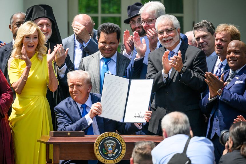 President Donald Trump holds up an executive order on the 