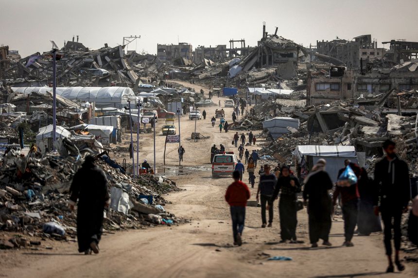 People walk past the rubble of destroyed buildings in the Jabalia camp for Palestinian refugees in the northern Gaza Strip on February 8, 2026. Since October 10, a fragile US-sponsored truce in Gaza has largely halted the fighting between Israeli forces and Hamas, but both sides have alleged frequent violations.
