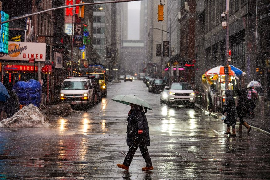 People walk along the street during snowfall on Sunday in New York City.