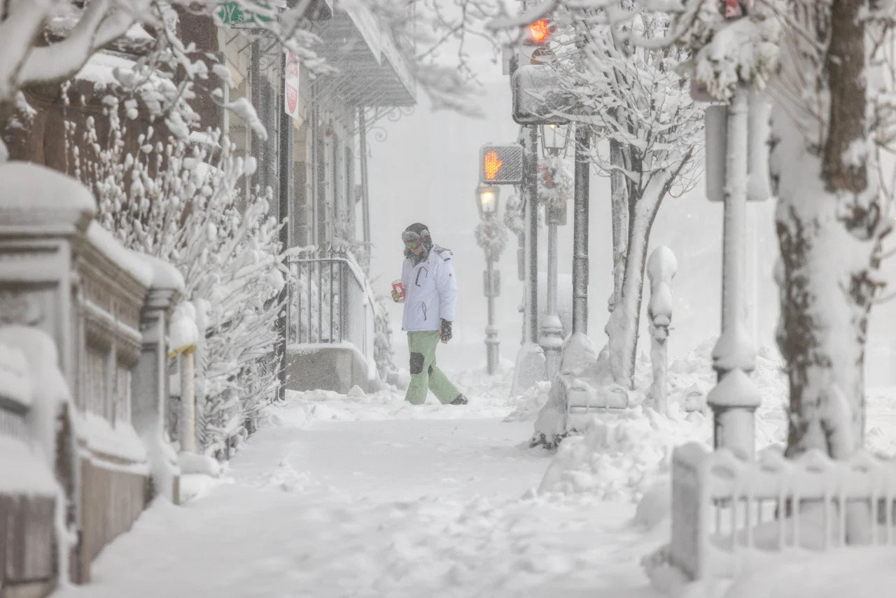 A person carries a drink during heavy snow in Boston.