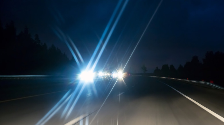 Blinding white headlights from oncoming traffic at night.