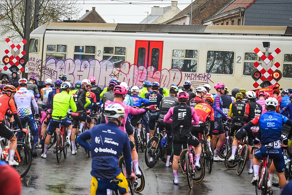 The peloton comes to a stop at a railway crossing during the 81st edition of the men's one-day cycling race Omloop Het Nieuwsblad (UCI World Tour), the opening race of the Flemish one-day classics season, 207,6 km from Gent to Ninove, Saturday 28 February 2026. BELGA PHOTO DAVID PINTENS (Photo by DAVID PINTENS / BELGA MAG / Belga via AFP)