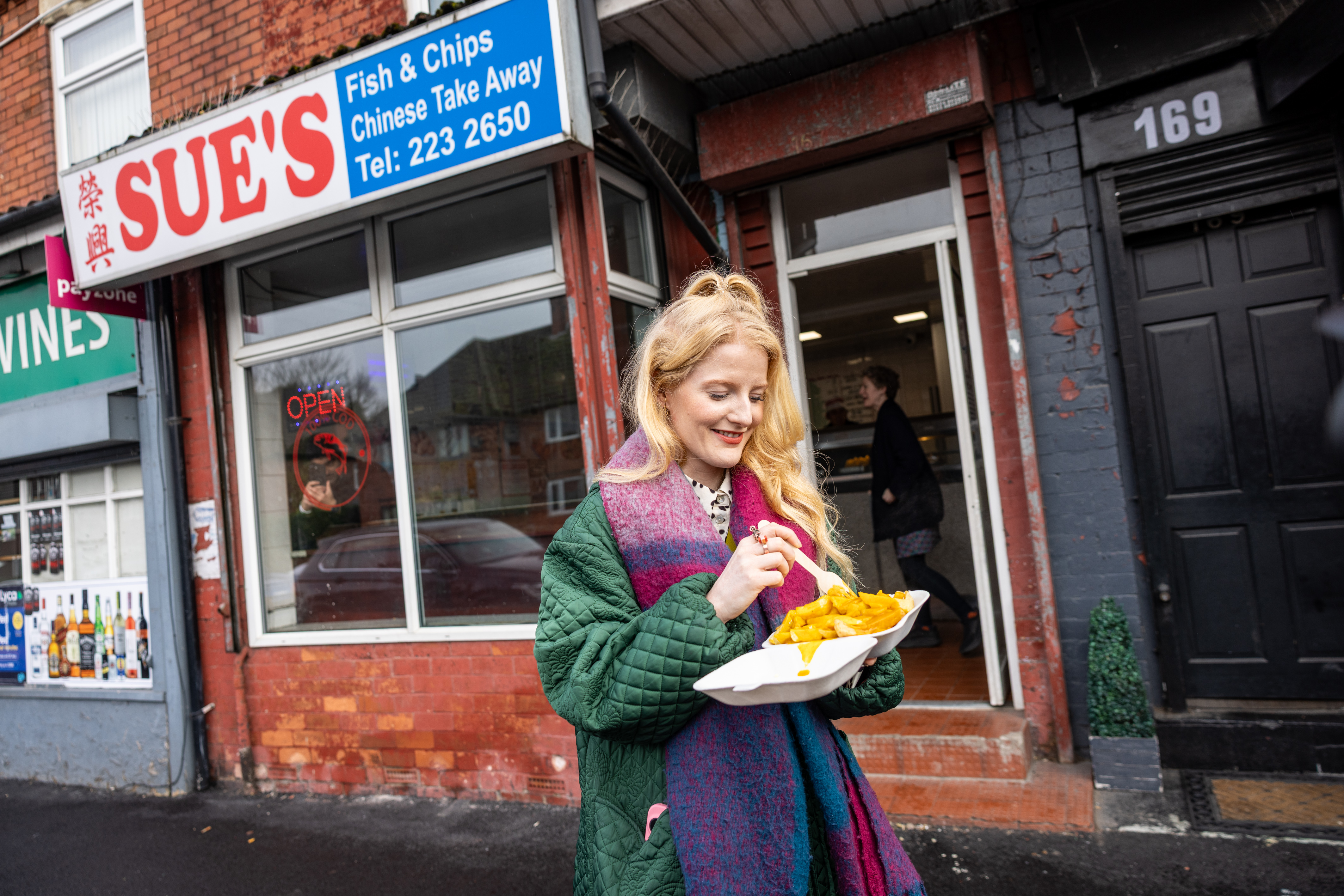 Green Party MP Hannah Spencer eats chips with curry sauce in Gorton.
