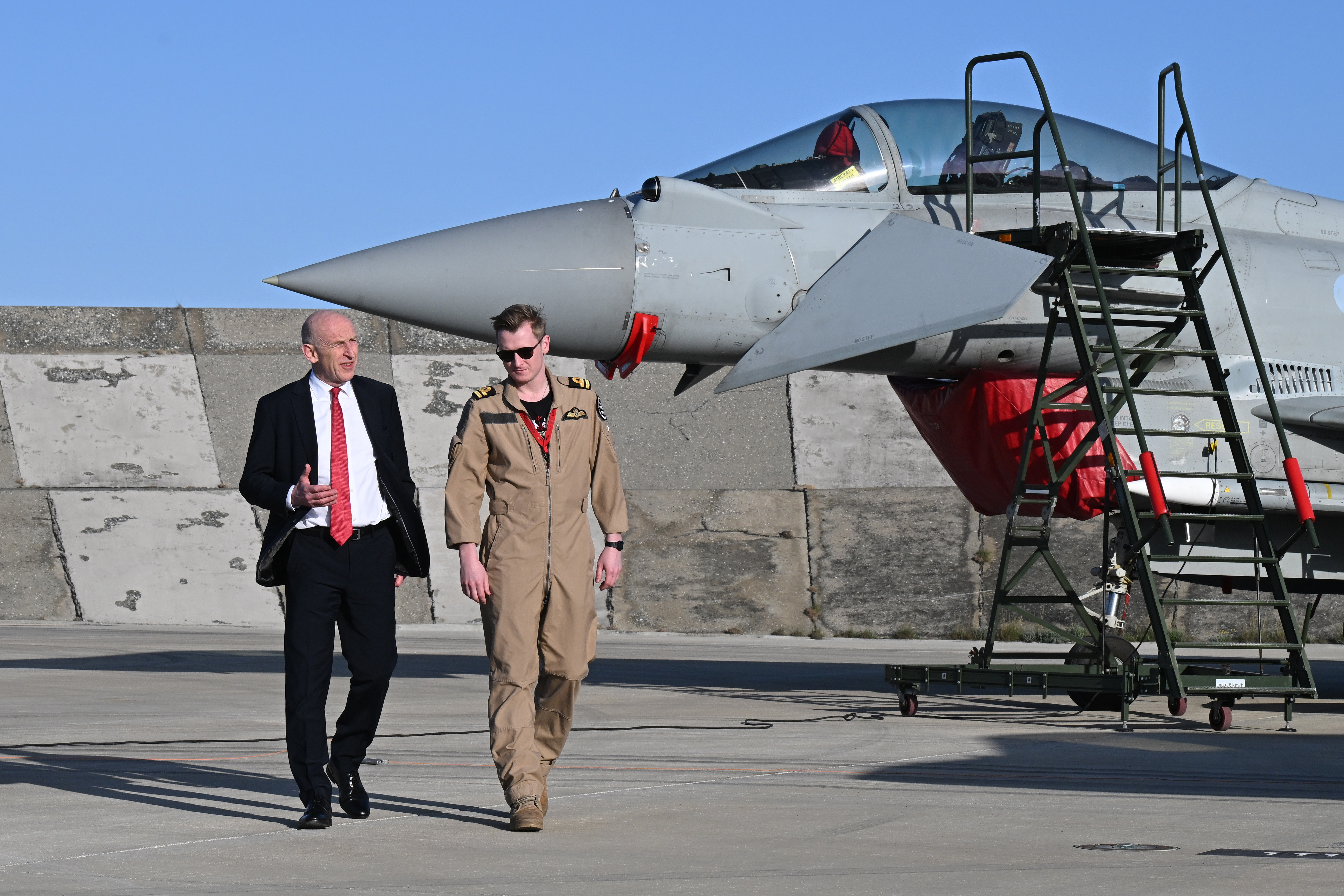UK Defence Secretary John Healey and an F-35 pilot walk past a British Typhoon jet at RAF Akrotiri.