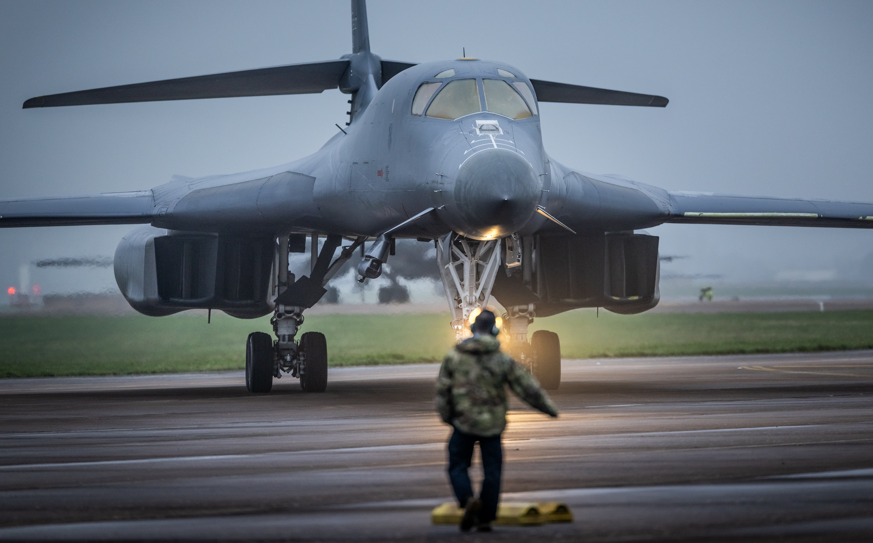 A member of the ground crew guides a USAF B1-B bomber onto the apron at RAF Fairford airbase.