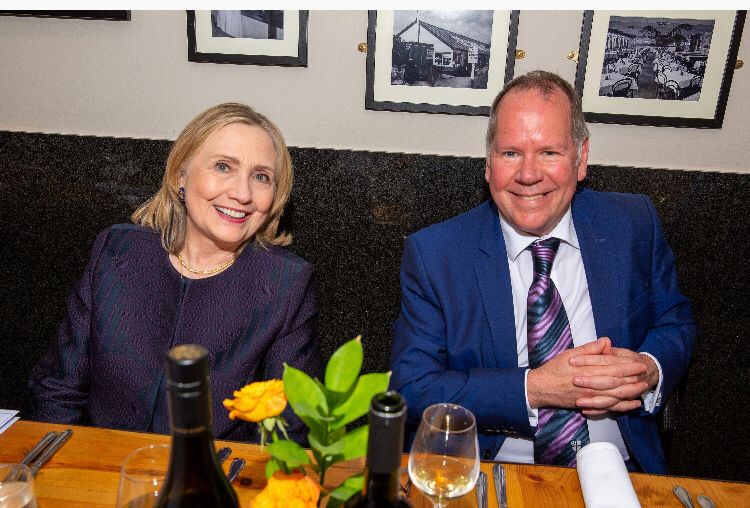 Hillary Clinton and Joe Docherty smiling at a table.