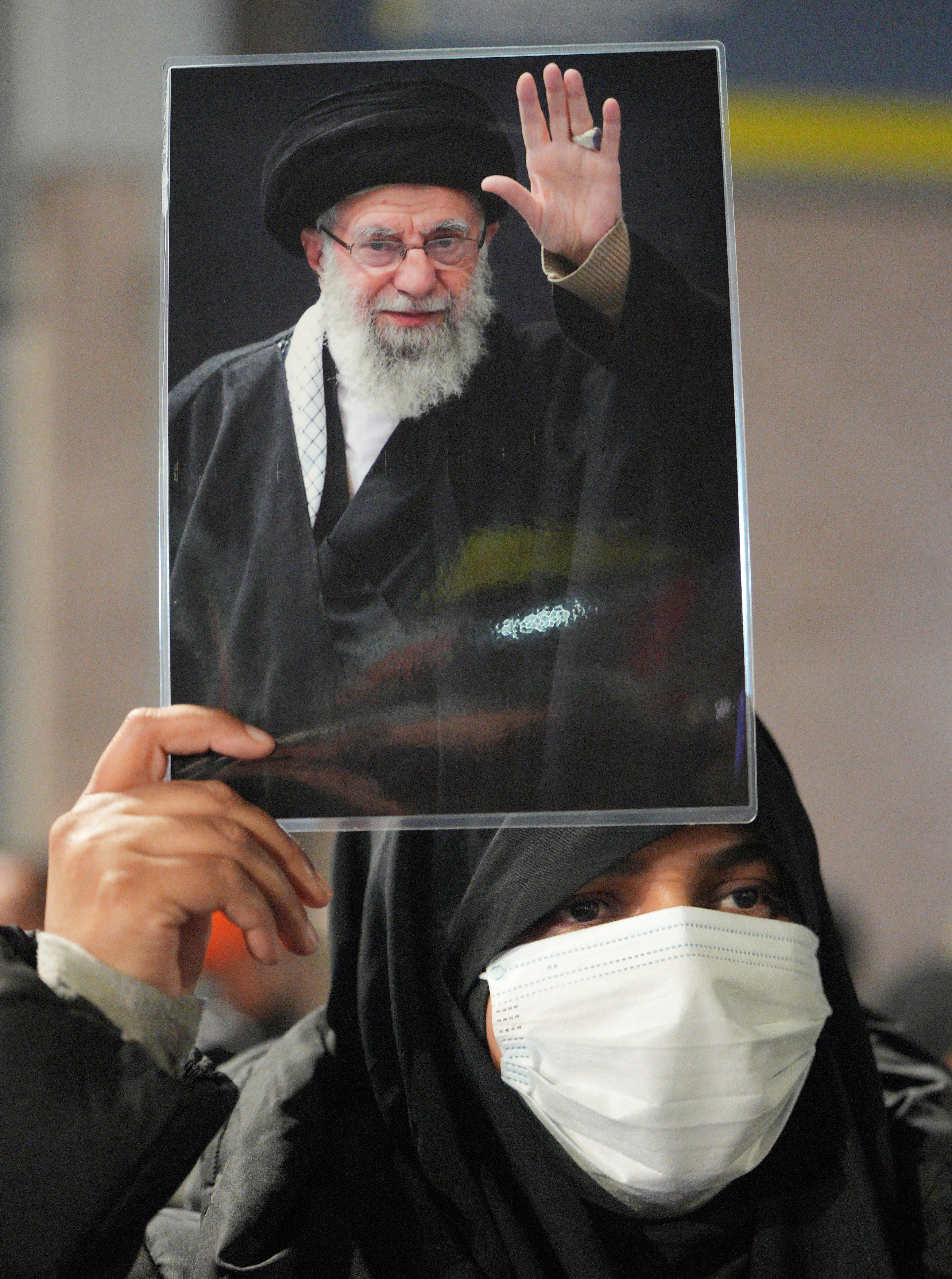 A protester holds a photo of the late ayatollah and a demonstration in favour of the Iranian regime