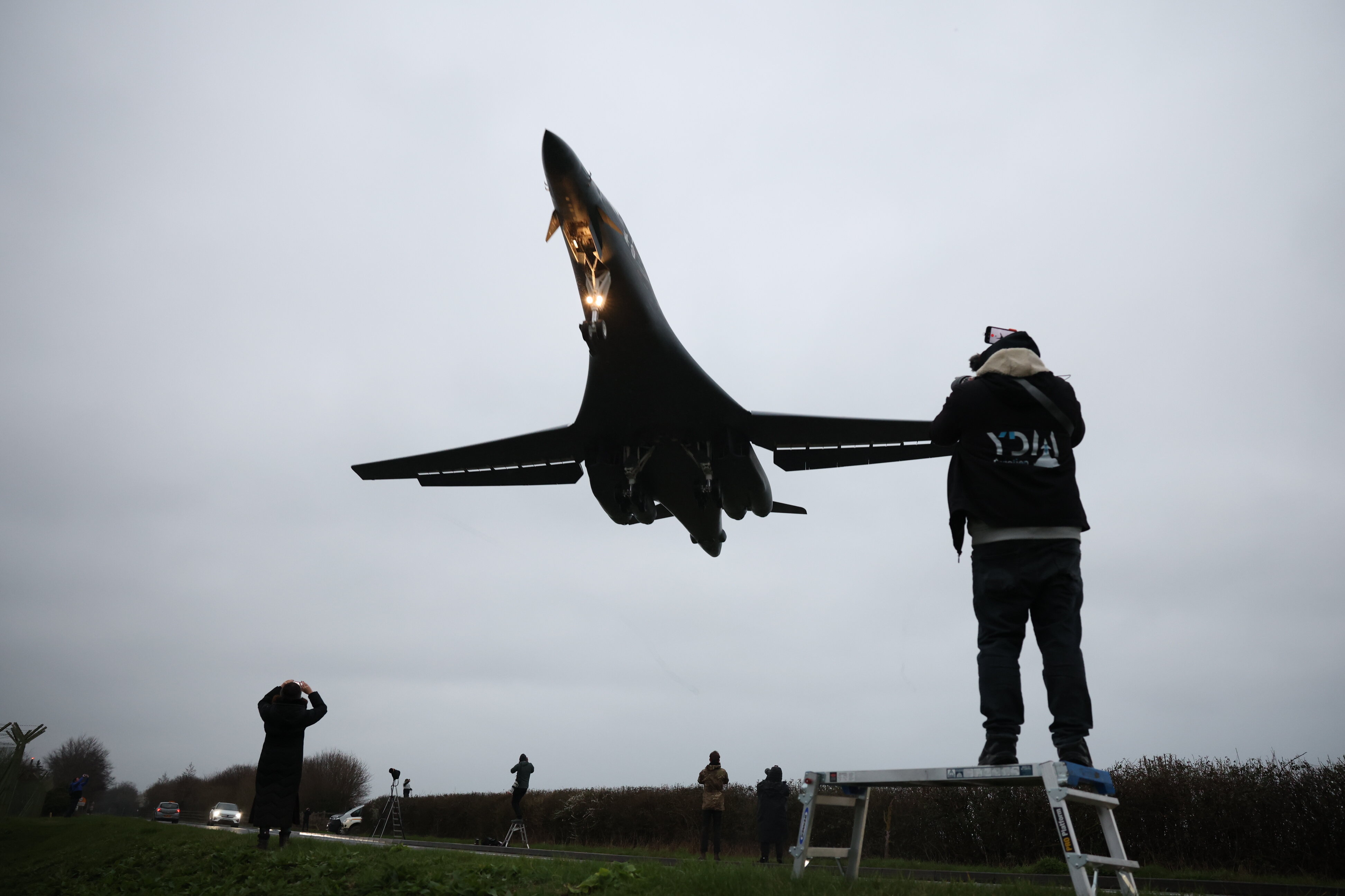 A B1B bomber descends over spectators on the ground.