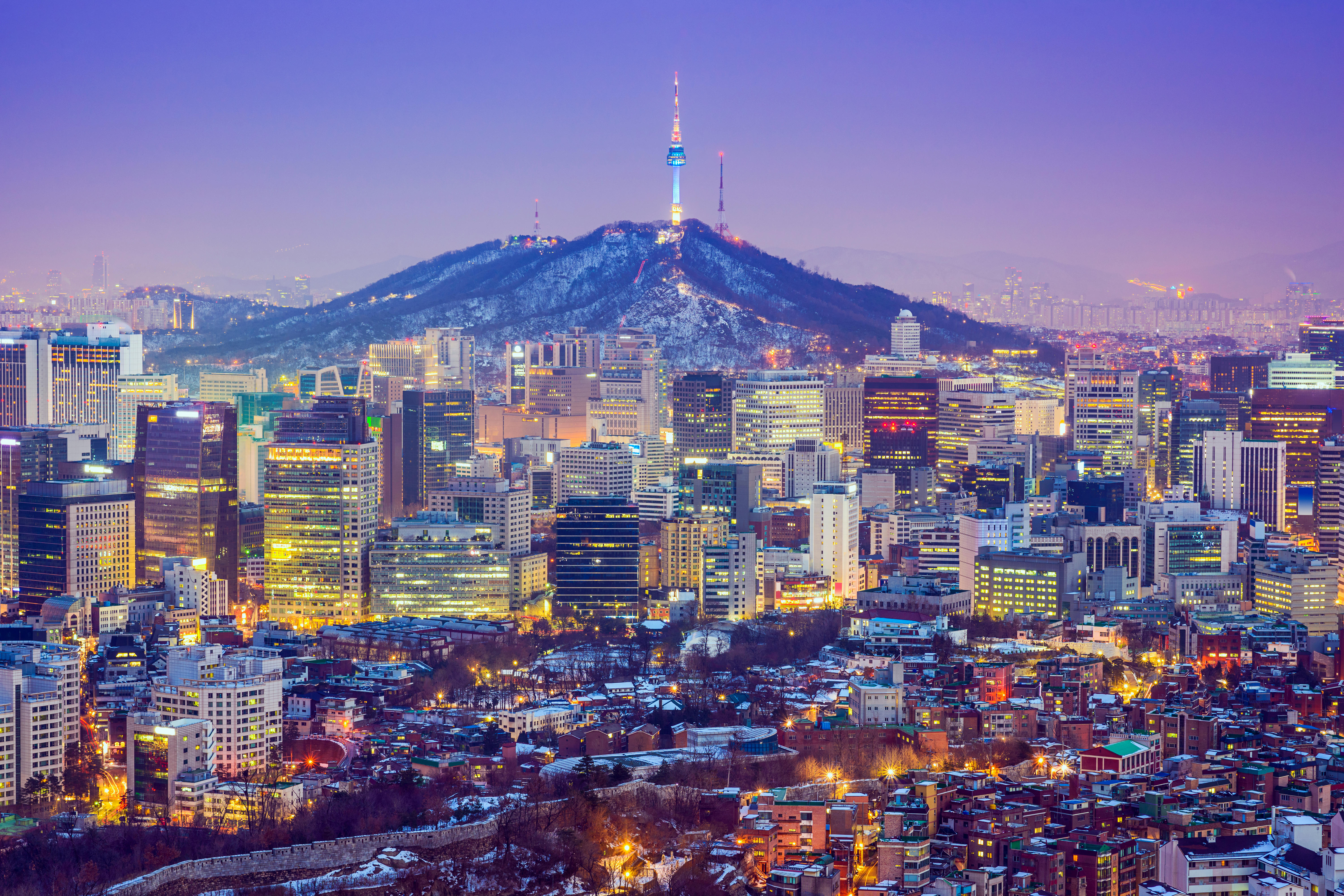 Seoul, South Korea city skyline at twilight with glowing buildings and Namsan Tower.