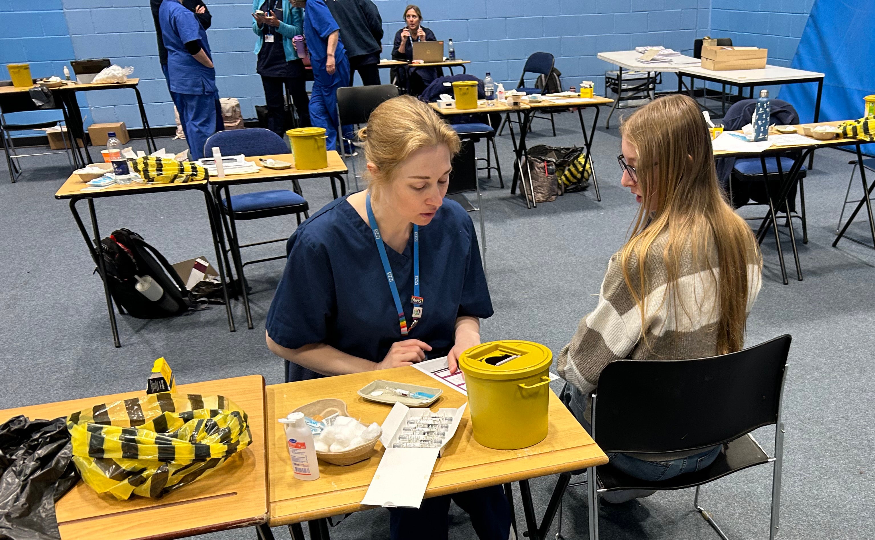 Students receiving vaccines and antibiotics from medical staff in the sports hall at the University of Kent