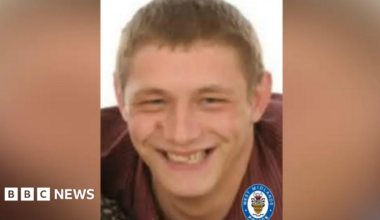 A man with short light brown hair and a maroon top