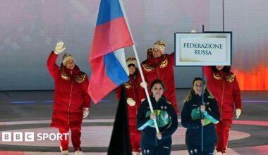 Members of the Russia team walk behind the Russia flag into the opening ceremony