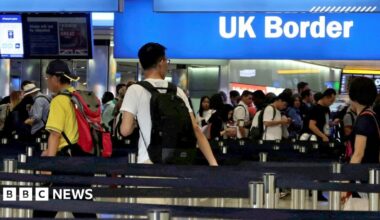 A busy border control area at Heathrow airport shows travellers queueing up to have their passports inspected, amid signs saying 'UK border' and 'passports', taken in 2017.