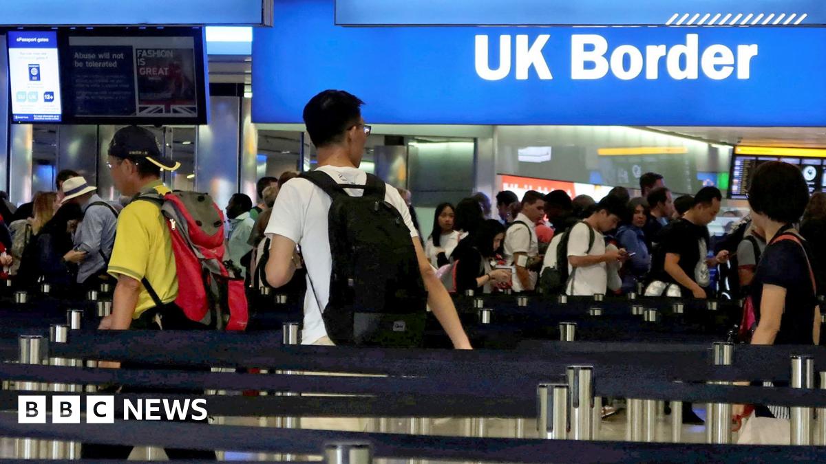 A busy border control area at Heathrow airport shows travellers queueing up to have their passports inspected, amid signs saying 'UK border' and 'passports', taken in 2017.