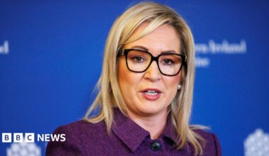 Several vehicles are seen on a multi-lane road in Abu Dhabi as smoke billows from Zayed port in the distance in the left of the picture