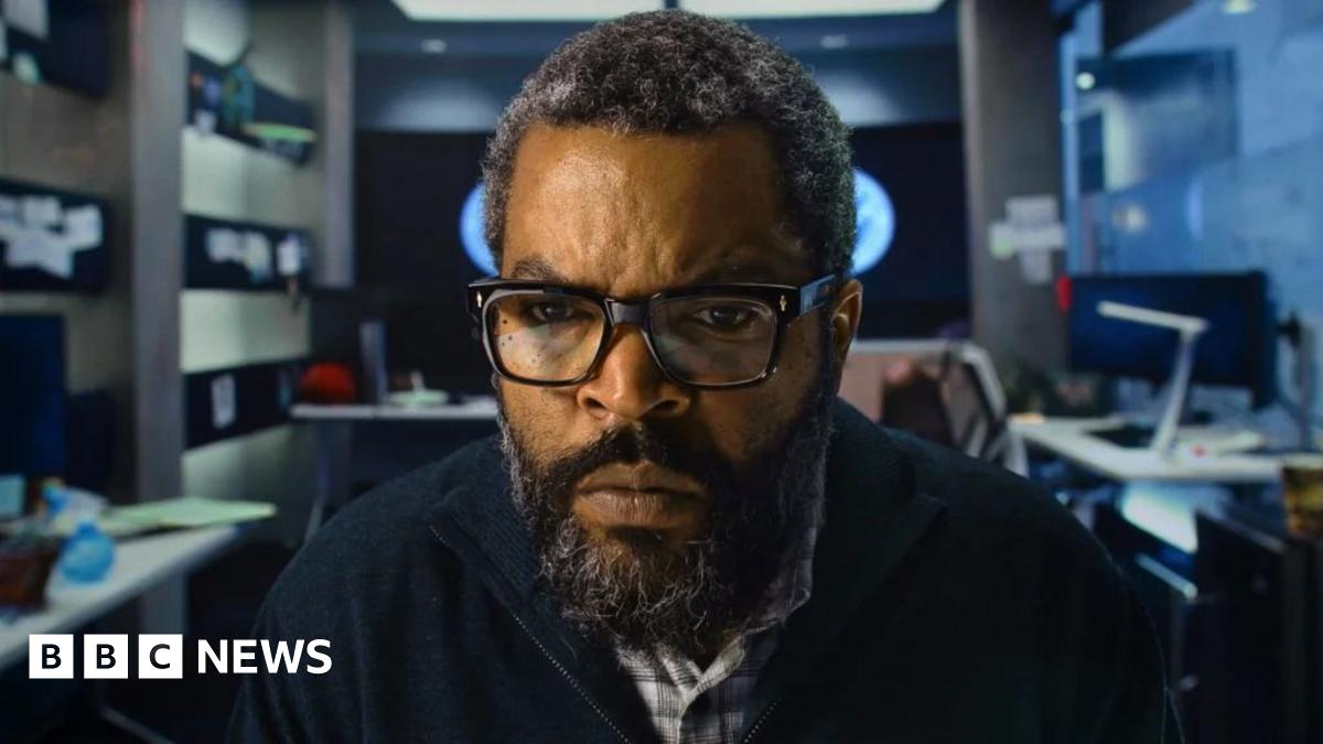 Ice Cube in an office facing the camera and staring intently at a screen