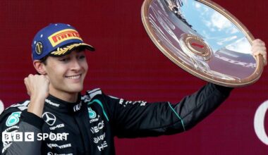 Mercedes' George Russell clenches his fist and lifts up the winner's trophy on the podium after the Australian Grand Prix