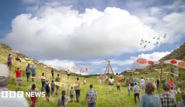 The Northern Lights shining over the Sycamore Gap at Hadrian's Wall in Northumberland, before it was illegally felled. The tree silhouette is illuminated by the pink and green light in the night sky.