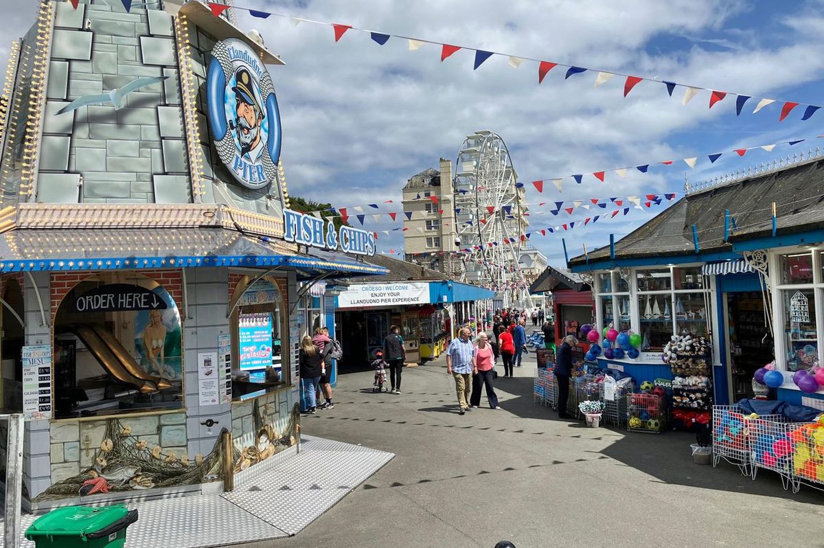 The entrance to Llandudno Pier with its arcades shops, funfair rides and food outlets.
